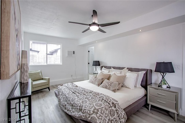 bedroom featuring ceiling fan, a wall mounted AC, and light wood-type flooring