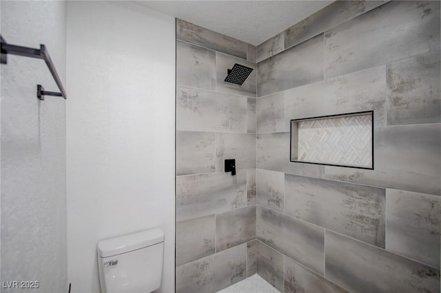 bathroom featuring toilet and a tile shower