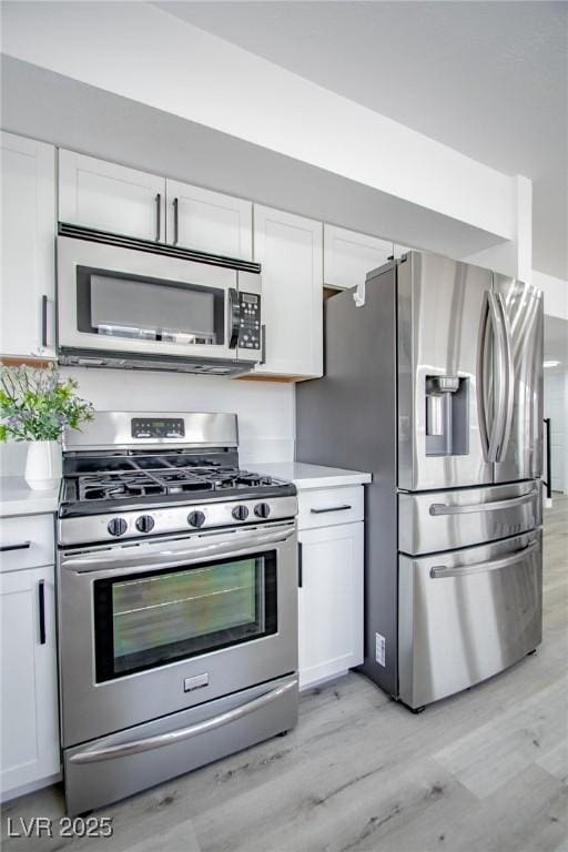 kitchen featuring appliances with stainless steel finishes, white cabinets, and light wood-type flooring