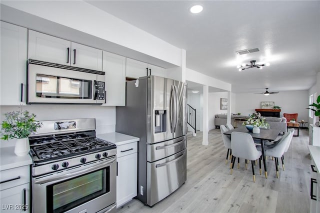 kitchen featuring appliances with stainless steel finishes, white cabinets, ceiling fan, and light hardwood / wood-style flooring