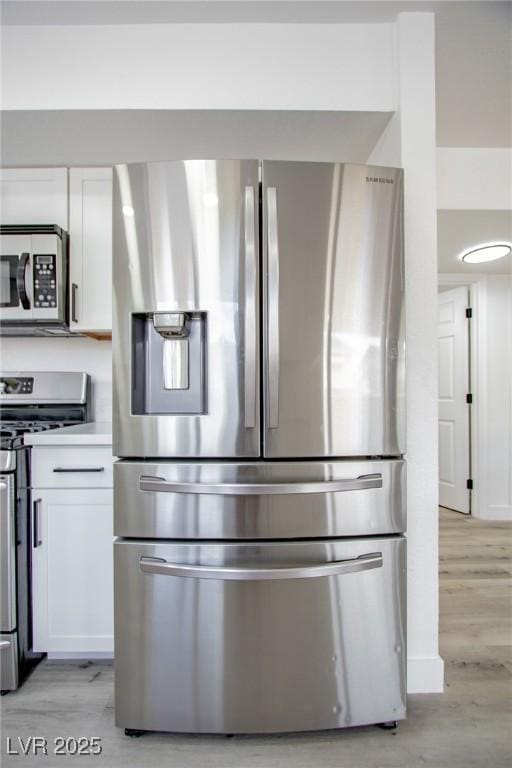 kitchen with white cabinetry, appliances with stainless steel finishes, and light hardwood / wood-style floors