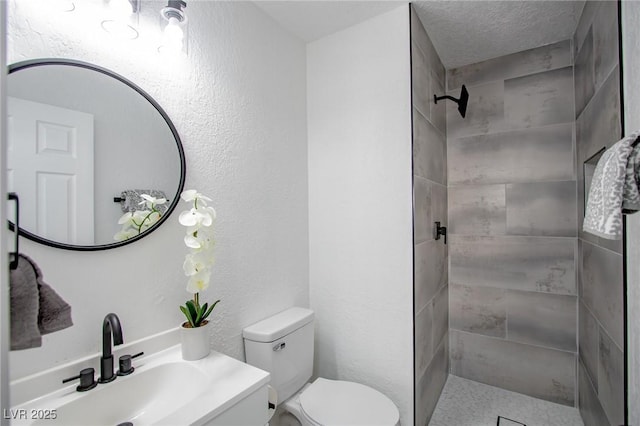 bathroom with vanity, a tile shower, a textured ceiling, and toilet