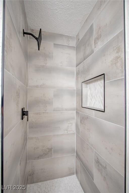 bathroom with a tile shower and a textured ceiling