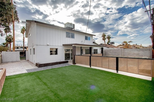 rear view of house featuring central AC and a lawn