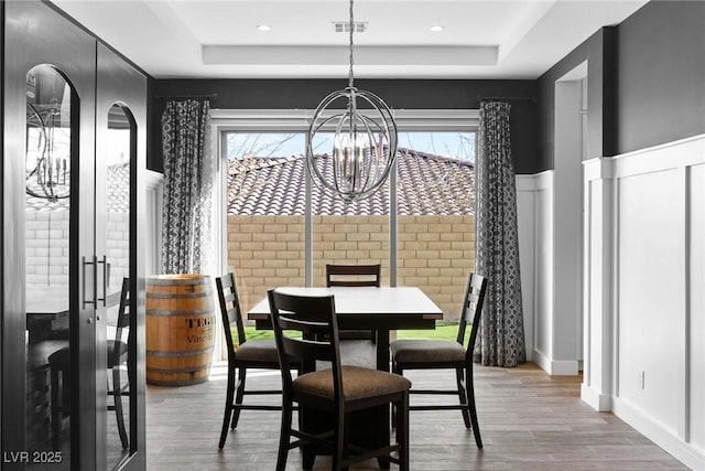 dining space featuring a tray ceiling, wood finished floors, and visible vents