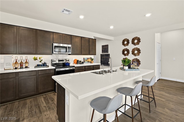 kitchen featuring sink, a center island with sink, a breakfast bar, and appliances with stainless steel finishes