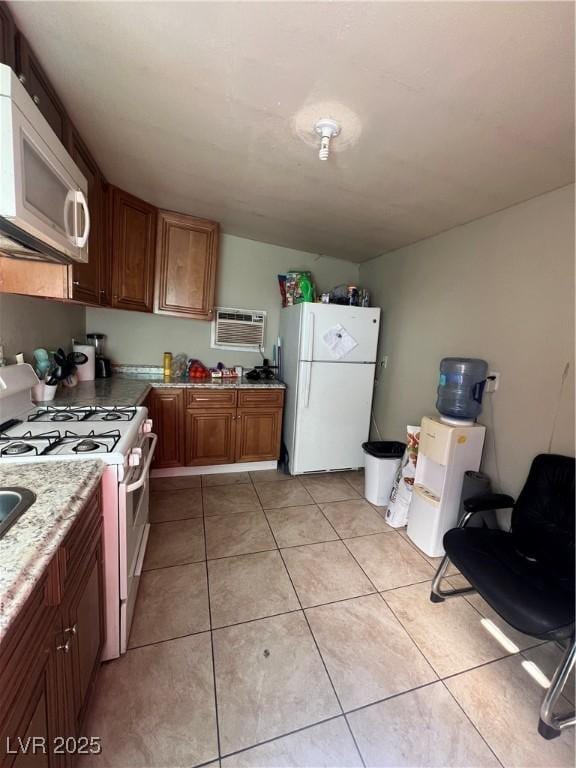 kitchen featuring a wall mounted AC, light tile patterned floors, and white appliances