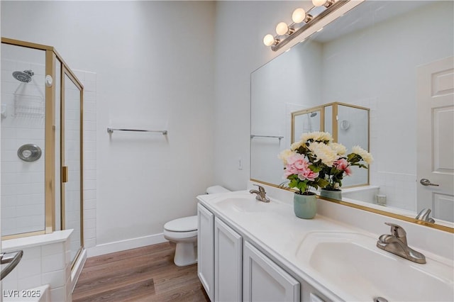 bathroom with toilet, vanity, a shower with door, and wood-type flooring