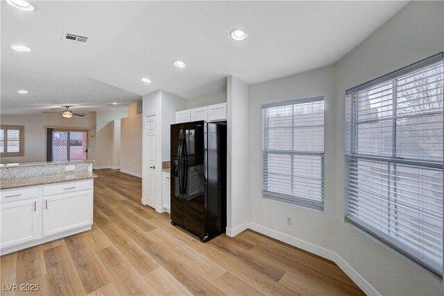 kitchen with light hardwood / wood-style flooring, black fridge with ice dispenser, ceiling fan, light stone counters, and white cabinets