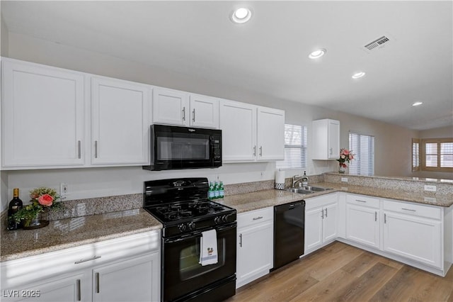 kitchen featuring sink, light wood-type flooring, black appliances, kitchen peninsula, and white cabinets