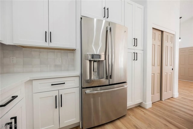 kitchen with backsplash, light hardwood / wood-style floors, stainless steel fridge with ice dispenser, and white cabinets