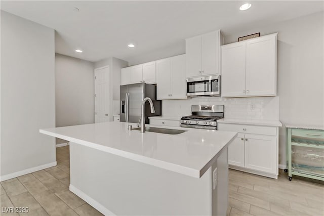 kitchen with a kitchen island with sink, sink, stainless steel appliances, and white cabinets