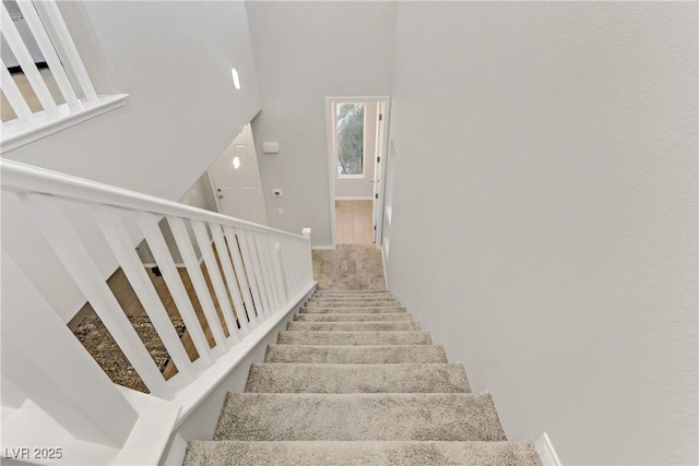 stairway featuring a towering ceiling