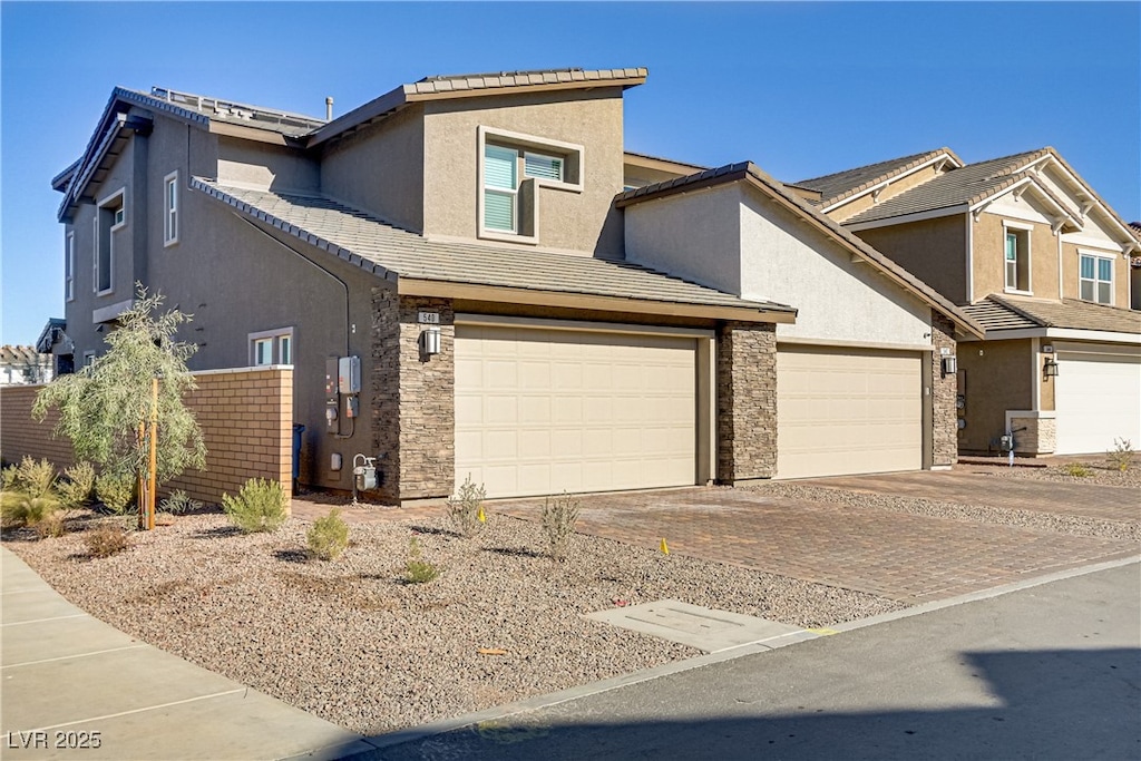 view of front of home featuring stone siding, decorative driveway, a tile roof, and stucco siding