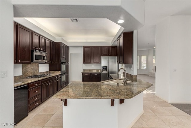 kitchen with stone countertops, sink, a breakfast bar area, stainless steel appliances, and light tile patterned flooring