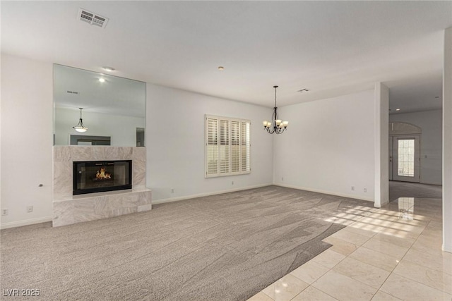 unfurnished living room with a notable chandelier, light colored carpet, and a premium fireplace