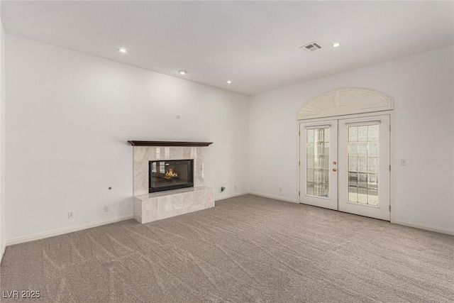 unfurnished living room featuring french doors, a premium fireplace, and carpet flooring