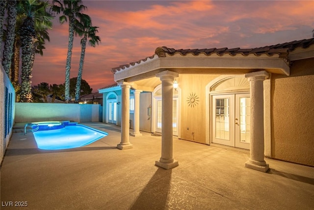 pool at dusk with french doors, a patio, and an in ground hot tub