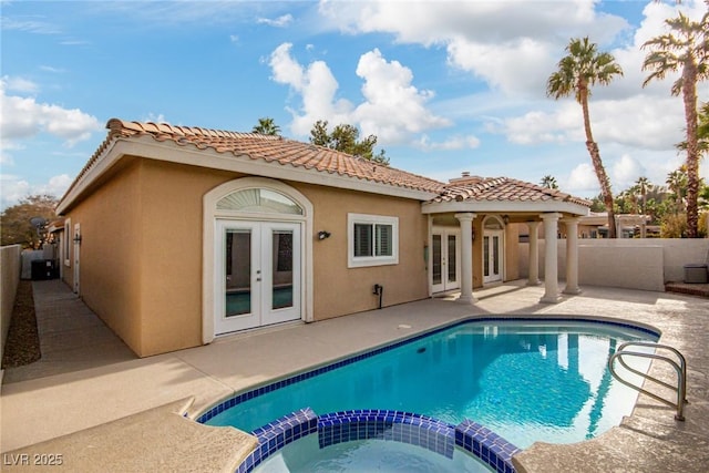 rear view of property with a patio, a pool with hot tub, and french doors