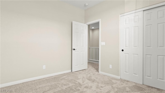 unfurnished bedroom featuring light colored carpet and a closet
