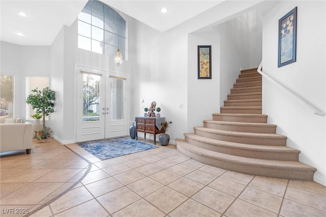 foyer entrance featuring light tile patterned floors, a towering ceiling, and french doors