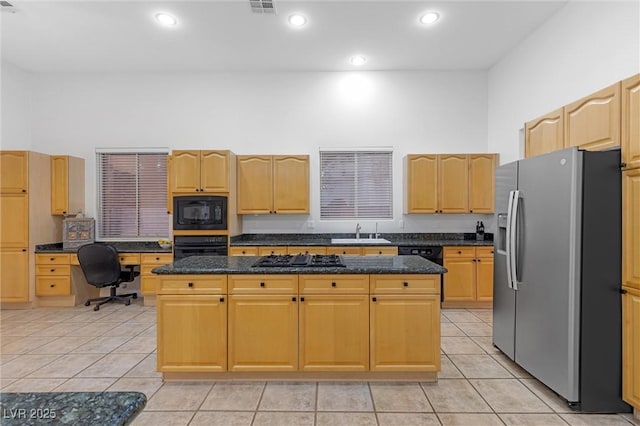 kitchen featuring a kitchen island, a towering ceiling, sink, dark stone countertops, and black appliances