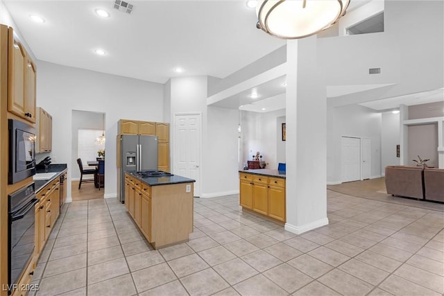 kitchen featuring light tile patterned floors, a kitchen island, black appliances, and a high ceiling