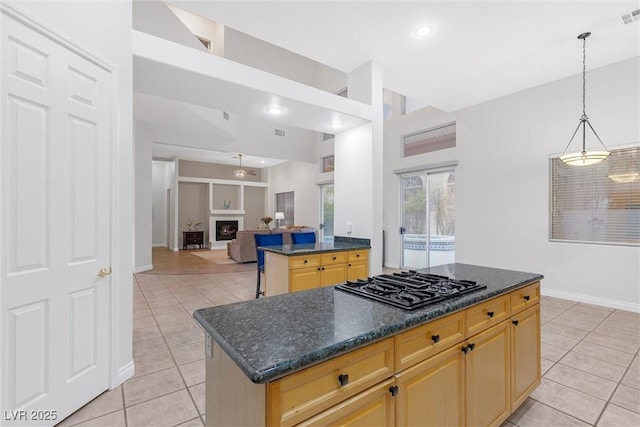 kitchen featuring a center island, black gas cooktop, light tile patterned flooring, light brown cabinetry, and dark stone counters