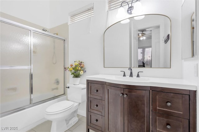 full bathroom featuring combined bath / shower with glass door, vanity, ceiling fan, toilet, and tile patterned floors