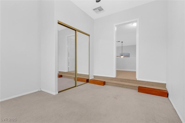 unfurnished bedroom featuring ceiling fan, light colored carpet, and a closet