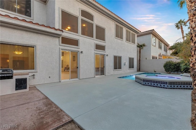 pool at dusk featuring an in ground hot tub, grilling area, and a patio area