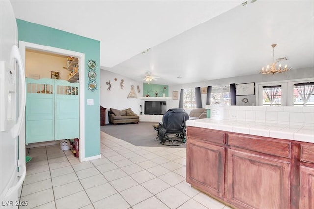 kitchen with white refrigerator with ice dispenser, a wealth of natural light, tile counters, and ceiling fan with notable chandelier