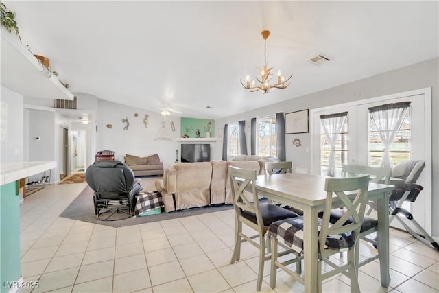 tiled dining area featuring ceiling fan with notable chandelier and french doors