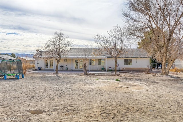 view of front of property featuring a patio area, a trampoline, and french doors