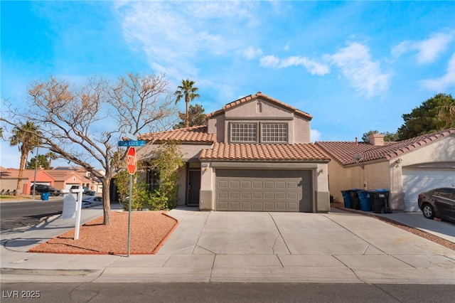mediterranean / spanish house with a tile roof, concrete driveway, a garage, and stucco siding