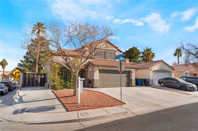 mediterranean / spanish house with stucco siding, driveway, a garage, a chimney, and a tiled roof