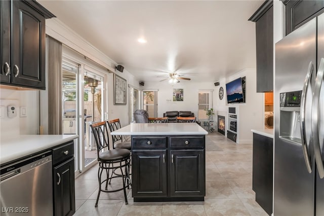 kitchen with open floor plan, appliances with stainless steel finishes, a breakfast bar, and light countertops