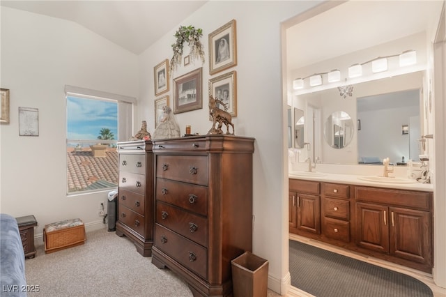 bathroom featuring lofted ceiling, double vanity, baseboards, and a sink