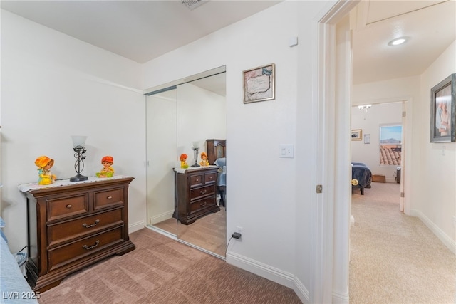 bedroom featuring a closet, light colored carpet, and baseboards