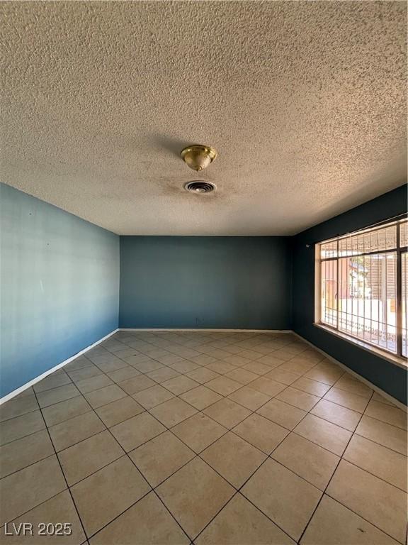 tiled spare room featuring a textured ceiling