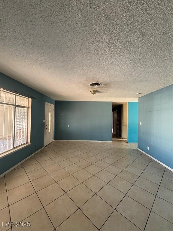 tiled spare room featuring a textured ceiling