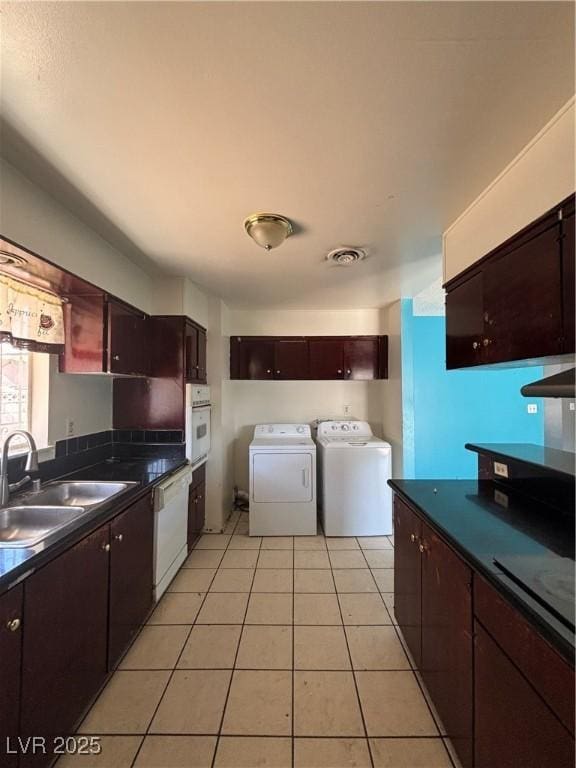 kitchen featuring visible vents, washer and clothes dryer, a sink, dark countertops, and white appliances