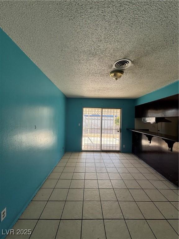 interior space with light tile patterned floors, visible vents, and a textured ceiling