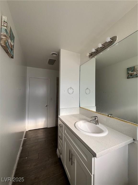 bathroom featuring visible vents, vanity, baseboards, and wood-type flooring