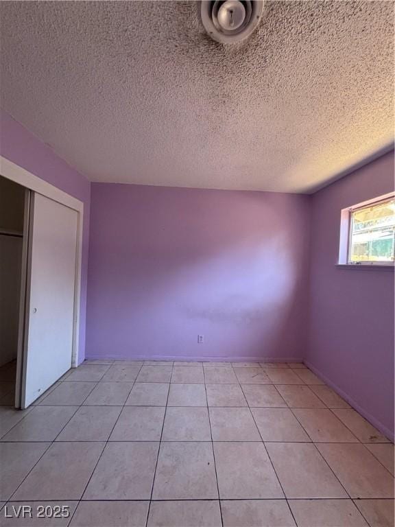 unfurnished bedroom with a closet, a textured ceiling, and light tile patterned flooring