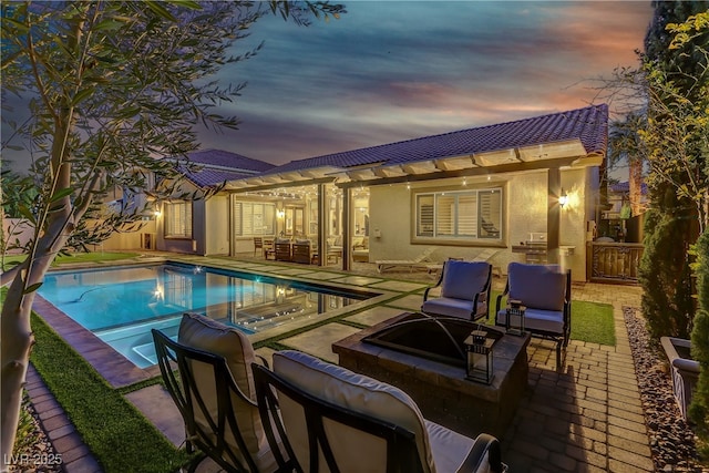 pool at dusk featuring an outdoor living space with a fire pit and a patio