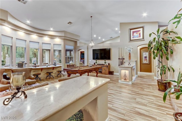 kitchen featuring light stone countertops, high vaulted ceiling, pendant lighting, and light wood-type flooring