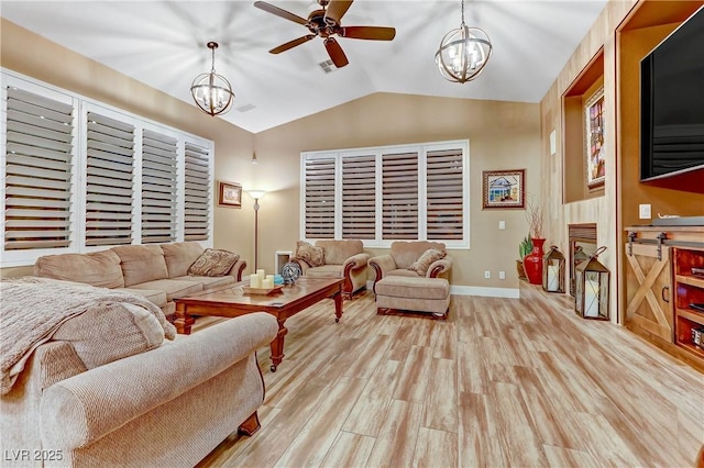 living room featuring lofted ceiling, ceiling fan with notable chandelier, and light hardwood / wood-style floors