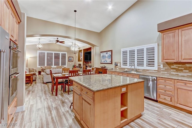 kitchen with a kitchen island, dishwasher, lofted ceiling, hanging light fixtures, and light stone counters