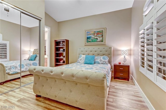 bedroom with hardwood / wood-style flooring, vaulted ceiling, and a closet